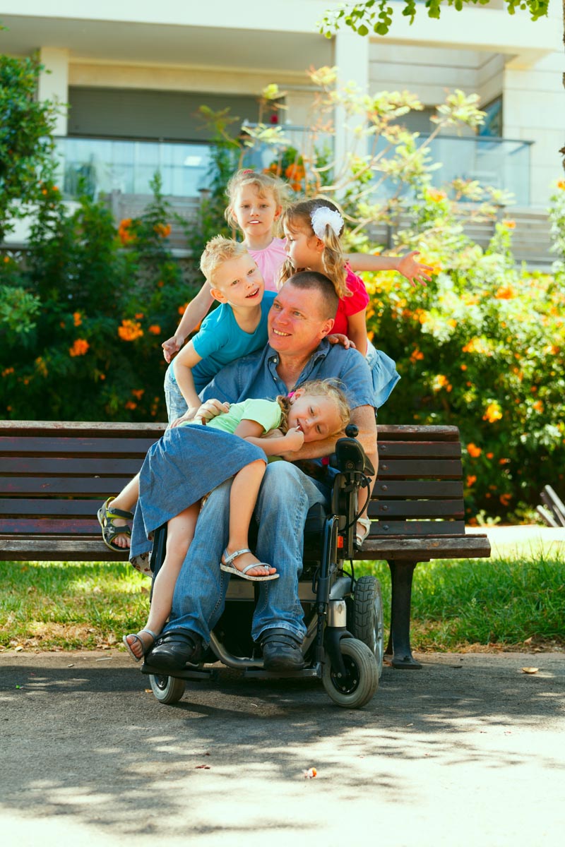 Dad in wheelchair children on lap on shoulders